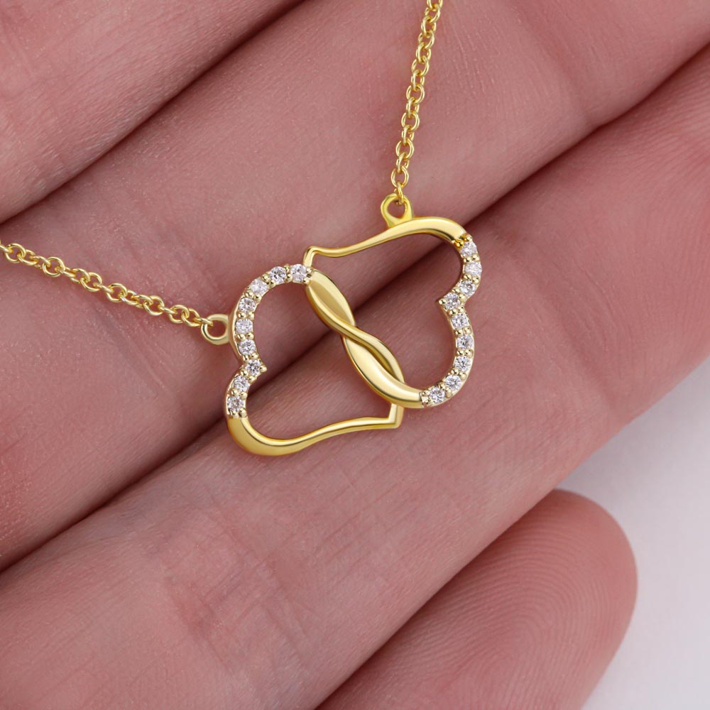 Close-up of double hearts necklace lying on someone's fingers