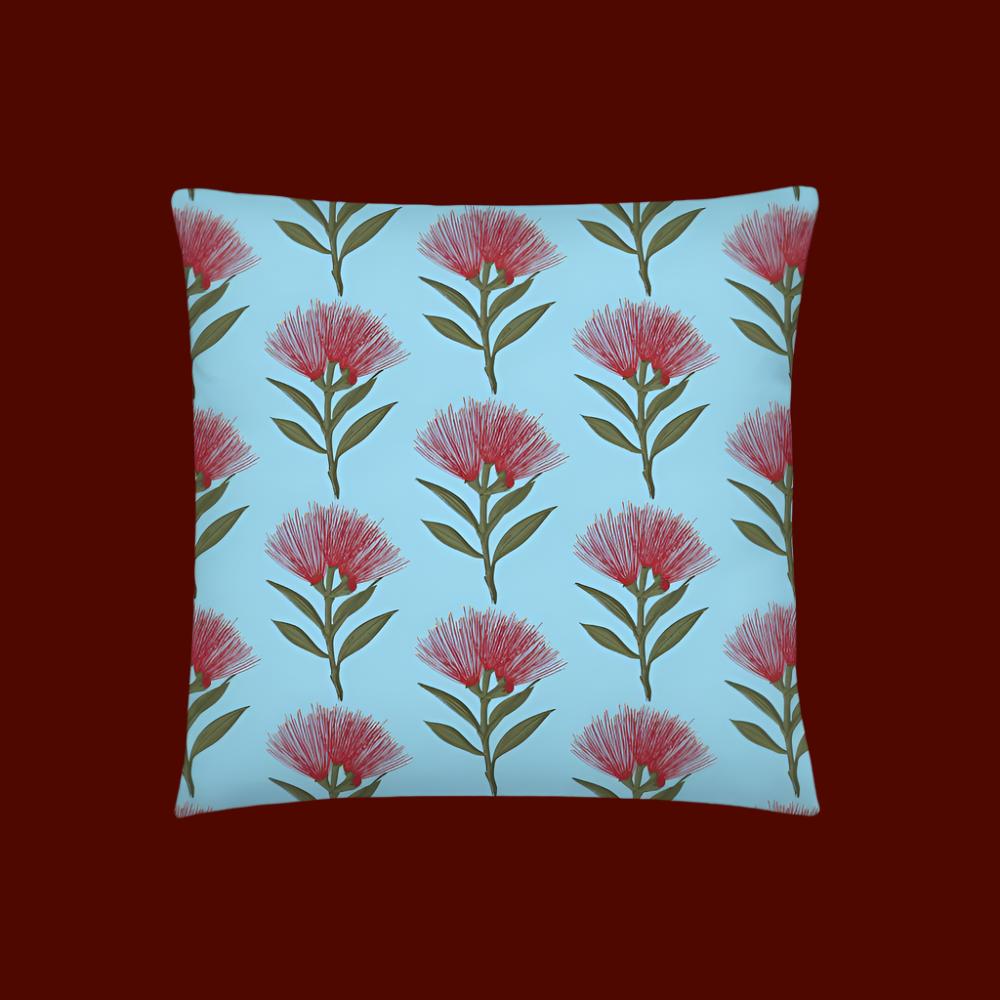 Pohutukawa print cushion with sky blue background being shown against a background of red square